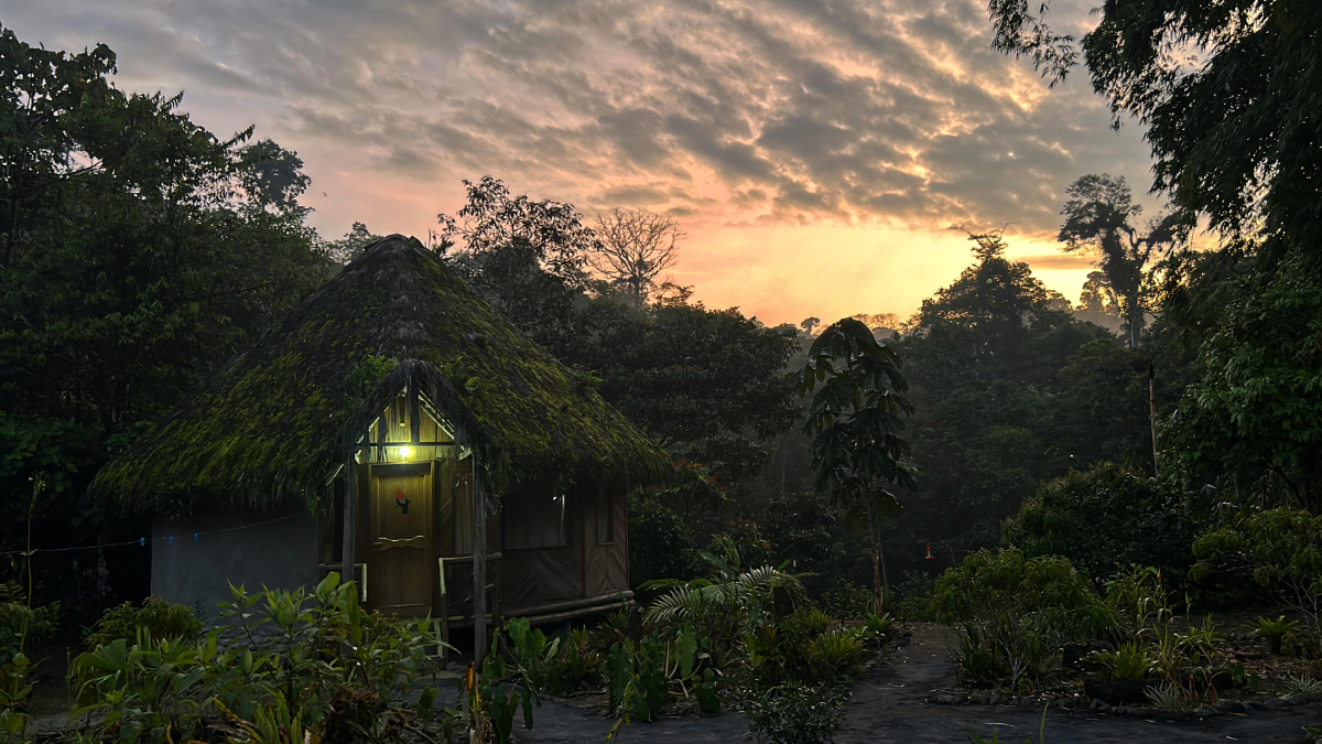 A light on the cabin glows in the evening light as the sunsets in the background at Amarun Pakcha