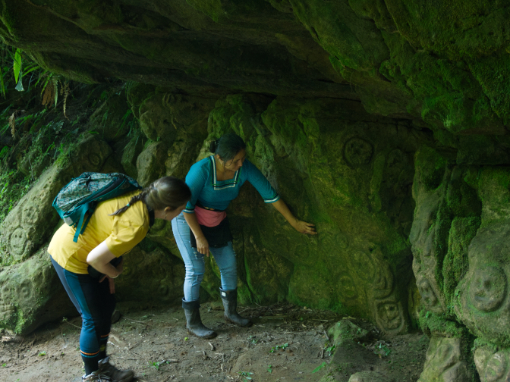 A Kichwa guide explains a petroglyph to a visitor at Amarun Pakcha, Ecuador