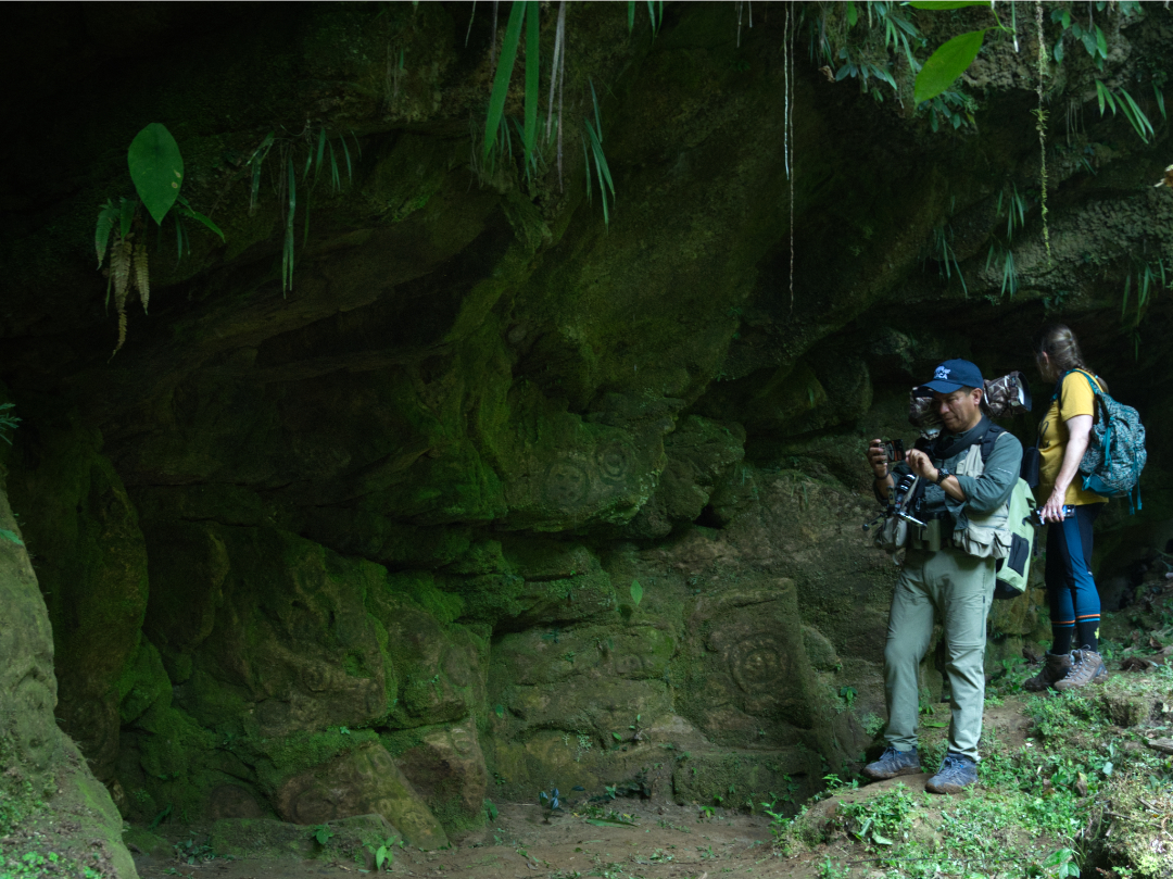 A man takes photos with his cellphone and camera of ancient petroglyphs